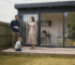 Family outside modern UK garden cabin