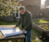 Man reviewing log cabin blueprints in garden