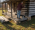 Man staining log cabin exterior for weatherproofing
