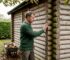 Homeowner inspecting log cabin wall outdoors