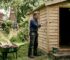 Man inspects timber cladding on garden cabin