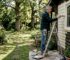 Man painting log cabin exterior in sunny garden