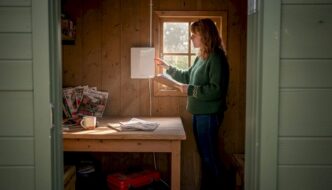 Woman evaluating heater in cozy garden cabin