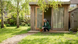 Homeowner beside modular cabin in spring garden