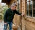 Homeowner inspecting garden log cabin exterior