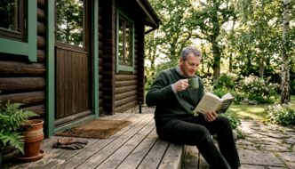 Man on timber deck outside log cabin